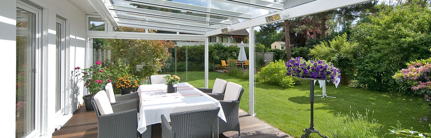 Terrassenansicht mit Blick in den Garten und weißem Terrassendach, an dem Heizelemente angebracht sind.