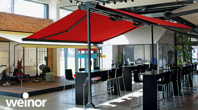 Freistehende Doppelmarkise mit rotem Tuch in einer Ausstellung.